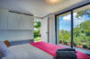 Bright bedroom in st barts villa with garden view through sliding glass doors.