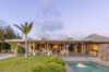 Elegant St Barts villa exterior with garden lawn, pool, and open terrace at sunset
