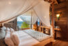 Romantic canopy bedroom with ocean view, natural wood interiors, and soft draped linens in a St Barts villa.