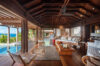 Spacious open-air living room with wooden interiors and poolside views at a luxury villa in St Barts.