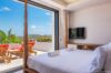Bright villa bedroom with terrace access, red loungers, and panoramic hillside views in a St Barts vacation rental.