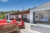 Spacious villa terrace with red lounge chairs, wooden deck, and seamless access to bedrooms in a St Barts vacation rental.