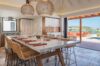 Stylish indoor dining area with rattan chairs, pendant lights, and open view of pool terrace in St Barts villa.