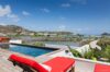 Private pool deck with red loungers overlooking the lagoon and hills in a luxury St Barts villa rental.