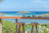Ocean-view breakfast bar with wooden stools overlooking turquoise waters in a St Barts villa rental.