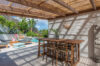 Shaded terrace with wooden dining table overlooking poolside loungers and tropical greenery in a St Barts villa rental.