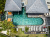 A majestic villa nestled amid vibrant greenery, its elegant architecture contrasting with the wild beauty of nature from a soaring aerial perspective.