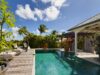 Private pool with sun loungers surrounded by lush tropical gardens at a St Barts villa.
