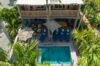 Two-story St Barts villa with wooden balconies, sun loungers, and private pool surrounded by tropical palms.