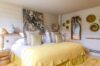 Bright bedroom in a St Barts villa with yellow bedding, tropical artwork, and natural decorative accents.