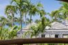 View of palm trees and stone-roofed pavilions from a St Barts villa with glimpses of the Caribbean Sea