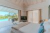 Serene villa bedroom in St Barts with ocean view through wide glass doors.