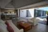 Modern open-plan living room with white sofa, wood coffee table, and seamless access to outdoor terrace at a St Barts villa rental