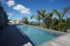 Elegant infinity pool with wooden deck, palm trees, and panoramic ocean views at a luxury St Barts villa rental