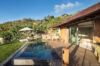 Sunlit deck with infinity pool beside modern villa bedroom in a private St Barts rental.