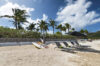 Private beachfront villa in St Barts with sun loungers, paddleboard, and swaying palm trees under a bright sky