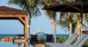 Oceanfront villa poolside in St Barts with sun loungers, palm trees, and a yacht in the distance