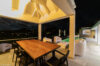 Covered outdoor dining terrace with warm lighting, lounge seating, and poolside views at night in a St Barts villa rental