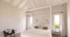 Bright villa bedroom with white four-poster bed, vaulted ceiling, and soft natural light in a St Barts vacation rental.