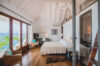 Luxury St Barthelemy villa suite featuring king bed and wide glass doors to sea views.