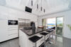 Sleek modern kitchen in a St Barts villa with black granite island, bar seating, and terrace views.