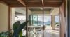 Dining area in a St Barts villa with glass doors opening to panoramic ocean and hillside views.