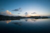 Infinity pool at a St Barts villa reflecting the sunset sky with hills and ocean horizon in the distance.