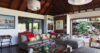 Stylish living room in a St Barts villa with vaulted wooden ceiling, colourful cushions, and terrace access.