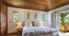 Cozy bedroom in a St Barts vacation rental with wooden ceiling, soft lighting, and garden view.