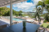 Shaded terrace dining table with tropical garden views overlooking a pool and hillsides at a St Barts villa rental.