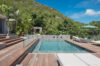 Wooden deck with infinity pool surrounded by tropical greenery at a hillside luxury St Barts villa rental.