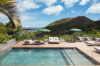 Infinity pool with glass railing, sun loungers, and hillside views at a luxury St Barts villa rental.