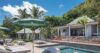 Luxury villa with pool, sun loungers, and tropical gardens set against a lush hillside in St Barts.