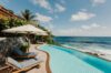 Curved infinity pool with sun loungers overlooking the Caribbean Sea at a luxury St Barts villa rental.