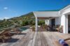 Wooden deck with lounge chairs and covered seating area beside the pool at a St Barths villa