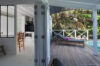 Cozy poolside terrace at a St Barts villa with sun loungers and a view into the bright kitchen.