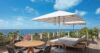 easide deck with lounge chairs, umbrellas, and round dining table overlooking the Caribbean at a St Barths villa.