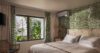 Tropical-inspired bedroom with palm leaf wallpaper and garden view at a St Barts villa rental.