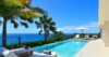 Infinity pool with sun loungers and palm trees overlooking the Caribbean Sea at a luxury St Barts villa.