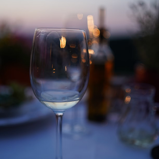 White wine glass with warm candlelight background at romantic dinner setting.