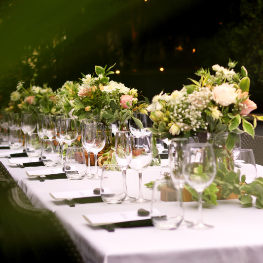 St. Barts villa outdoor anniversary dining: pristine white table with floral centerpieces, wine glasses, and elegant place settings.