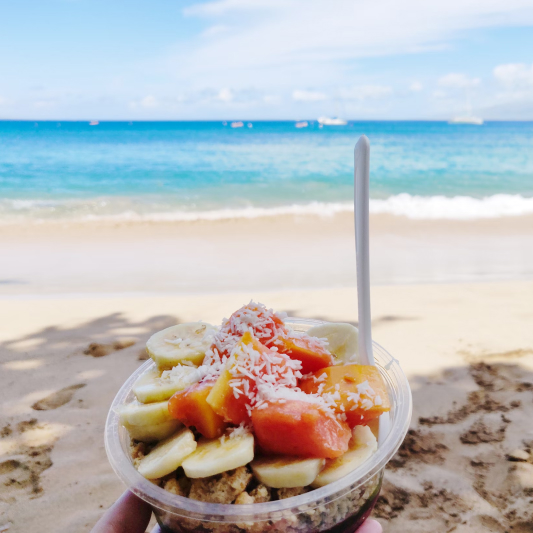 Fruit bowl on sandy beach by sea