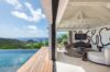 Contemporary living room with artistic wall design opening to infinity pool and ocean view at St Barts villa rental.