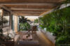 “Covered terrace in a St Barts villa with lounge seating, tropical plants, and harbor sunset views