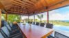 Open-air dining pavilion with a long wooden table, wicker chairs, and panoramic ocean views at a luxury villa in St Barts