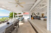 Covered terrace with dining table and lounge area overlooking ocean at St Barthelemy vacation rental.