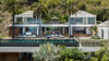 Luxury St Barts villa with infinity pool, palm trees, and modern glass-front design overlooking the Caribbean Sea