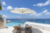 Luxury St Barts villa terrace with infinity pool, sun loungers under a white umbrella, and panoramic Caribbean Sea views