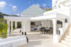 Elegant white villa terrace in St Barts with covered lounge and dining area, accented by lantern-style details and surrounded by tropical greenery