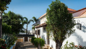 Pathway leading to a villa with red roof and surrounding greenery in Lurin